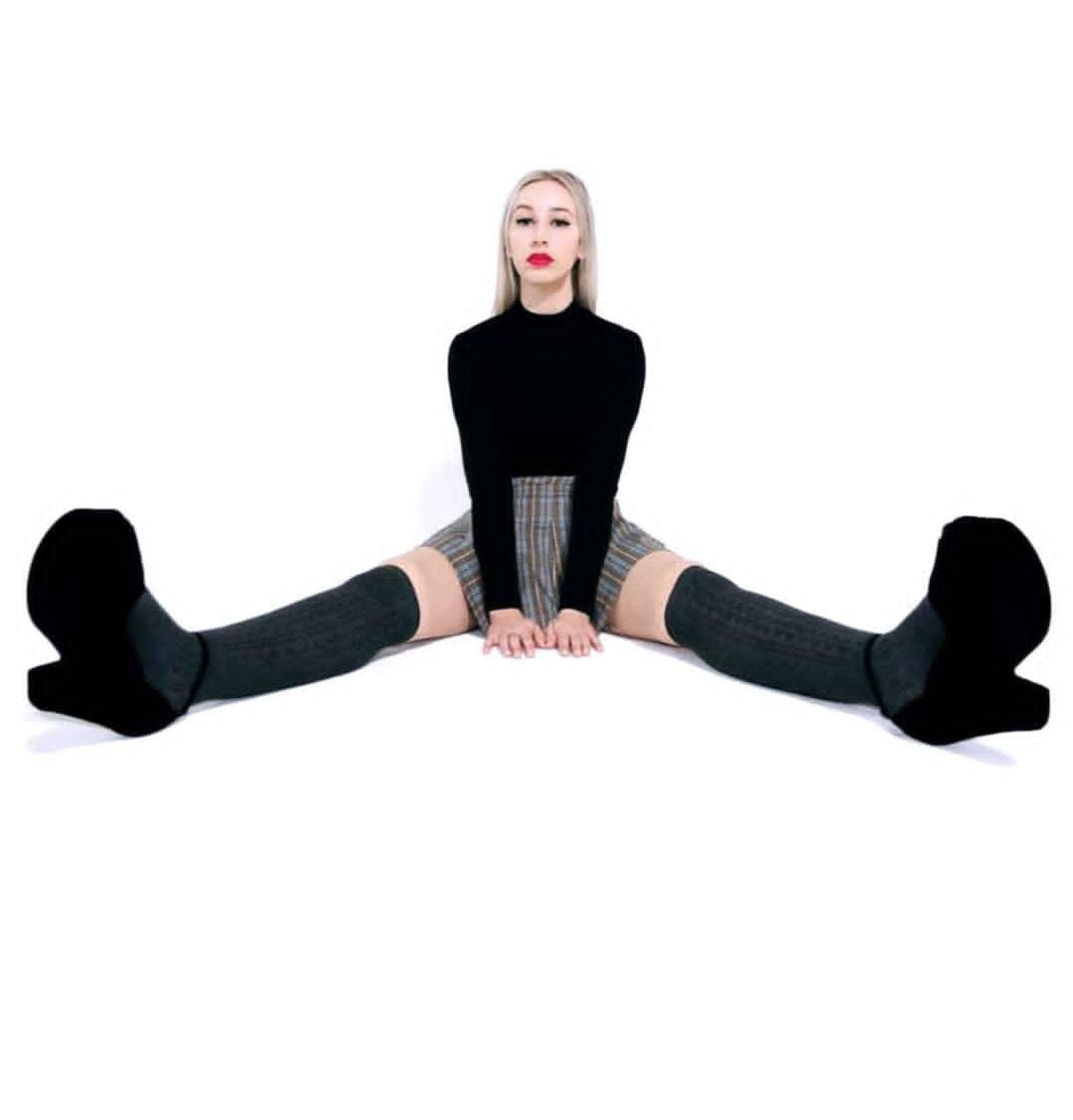 Elisabeth sitting in a splits pose on a white background